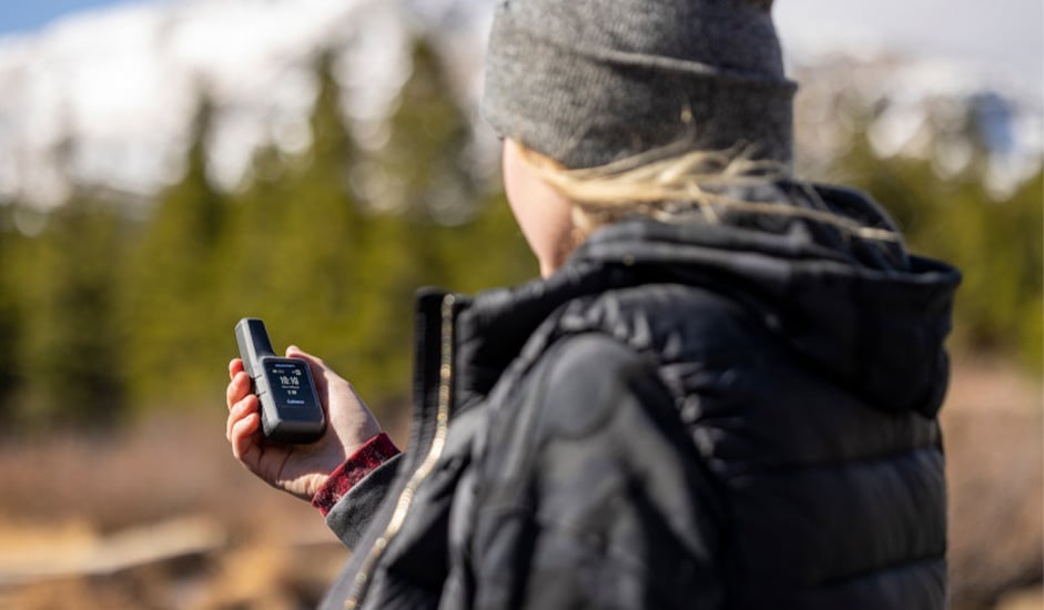 Vuoristossa oleva henkilö katsoo Garmin inReach-laitettaan.